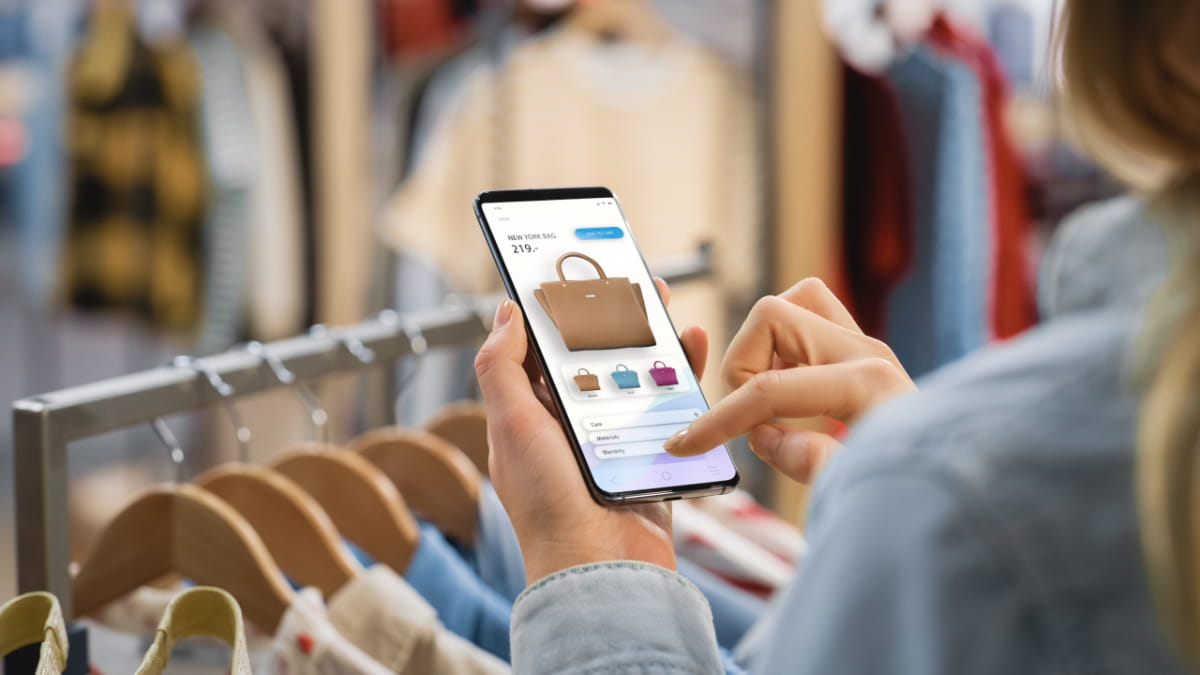 Eine Frau benutzt ihr Handy in einem Kleidungsladen
